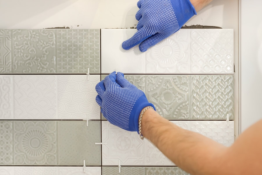 professional tiler working on wall tiling 